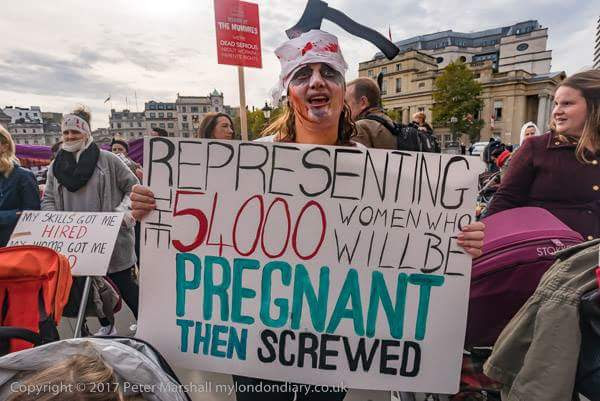 A woman dressed as a mummy with a sign reading 'Representing the 54,000 women who will be pregnant then screwed'