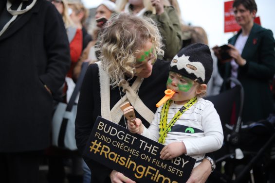 Image description: Woman with her baby at the March of the Mummies Protest 2017 with facepaints on holding a placard