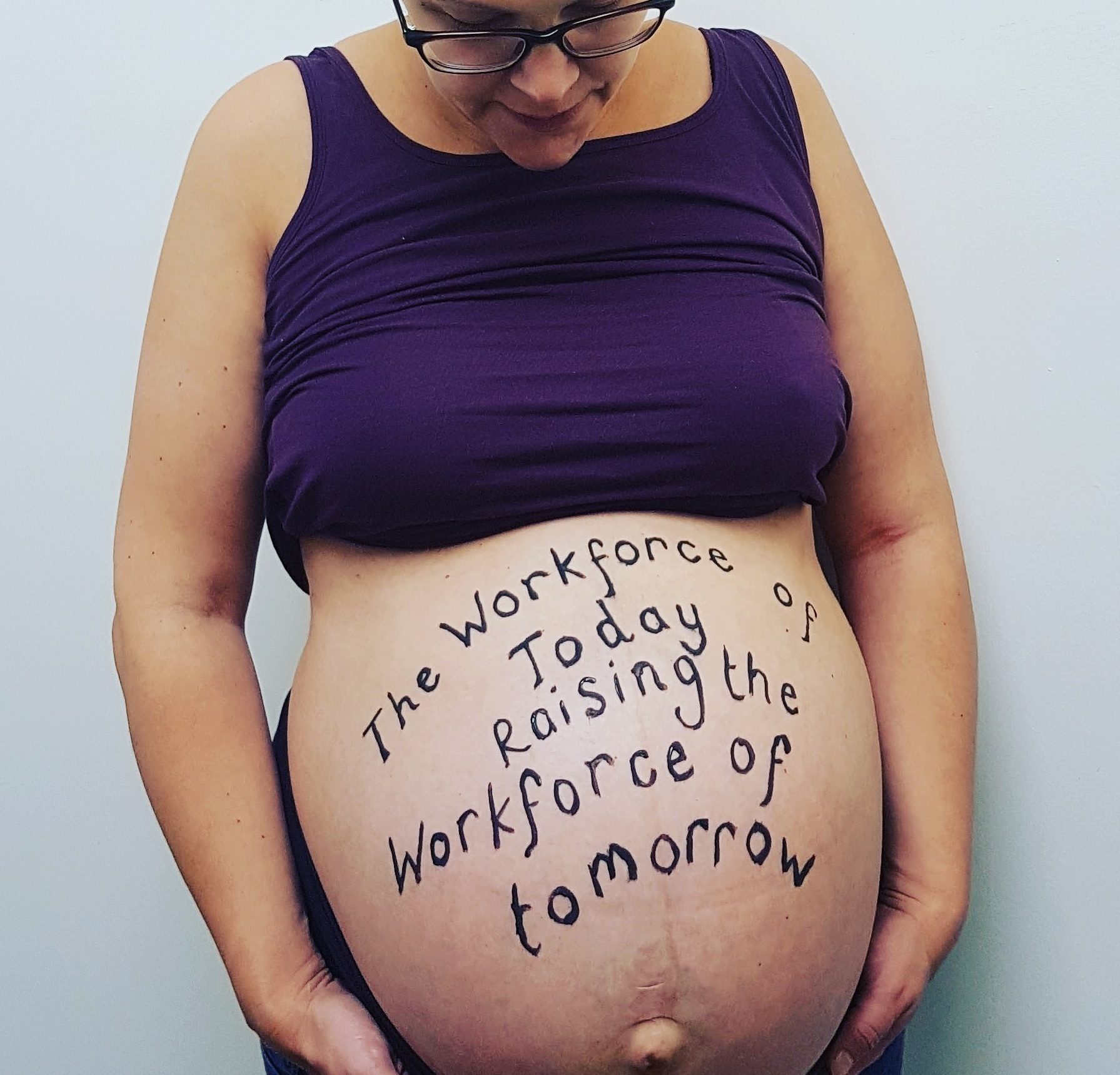 Pregnant woman with 'The workforce of today raising the workforce of tomorrow' written on her belly