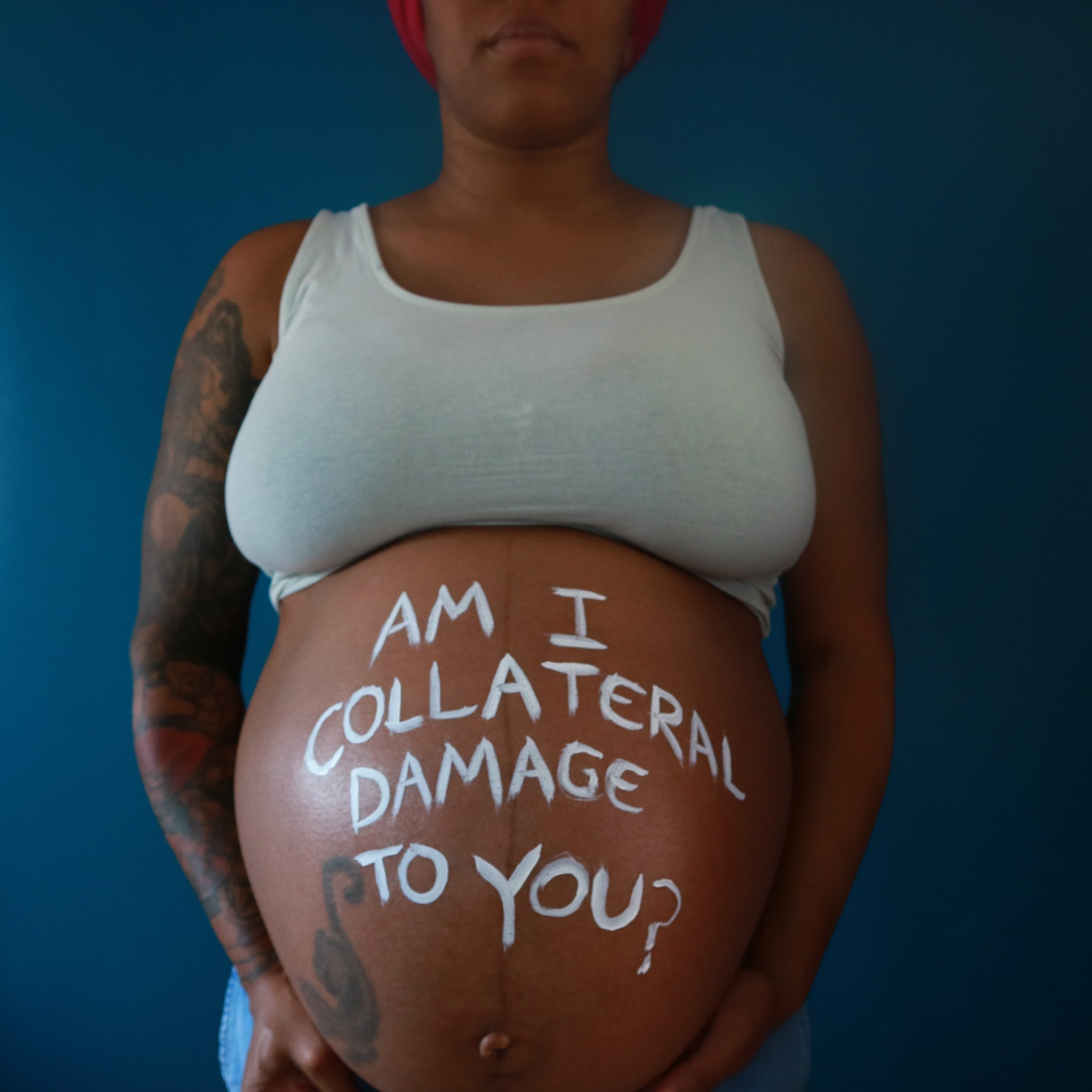 Image Description: Pregnant brown woman holding her belly, which has 