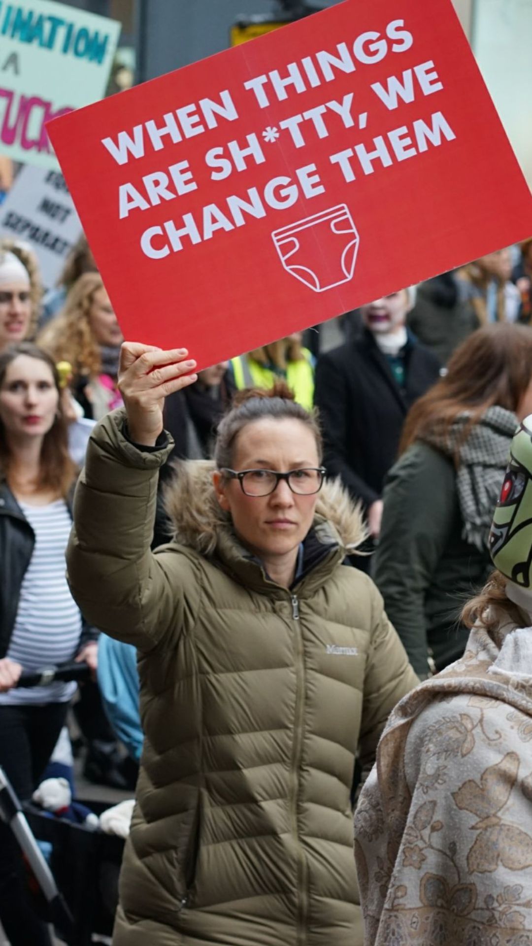 Image description: women protesting holding a placard that says 