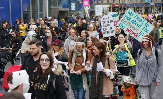 Alt text: protesters dressed in spooky costumes and placards at the March of the Mummies protests